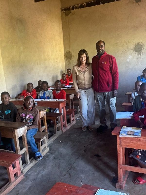 A classroom with children and two adults standing in the middle.