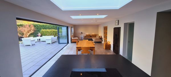 Modern open-plan kitchen and living area with skylights and patio seating.