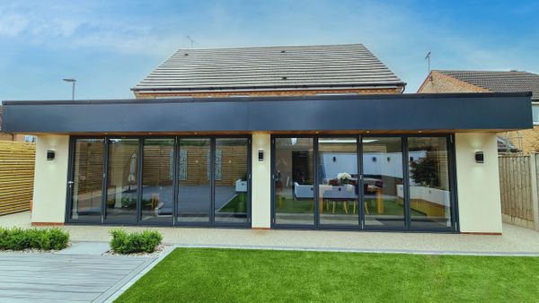 Modern backyard extension with large sliding glass doors and a manicured lawn.