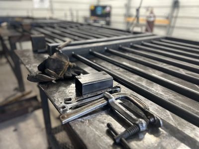 Welding gloves and metal tools on a steel workbench in a workshop.