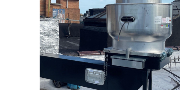 Industrial rooftop ventilation unit with ductwork under a clear sky.