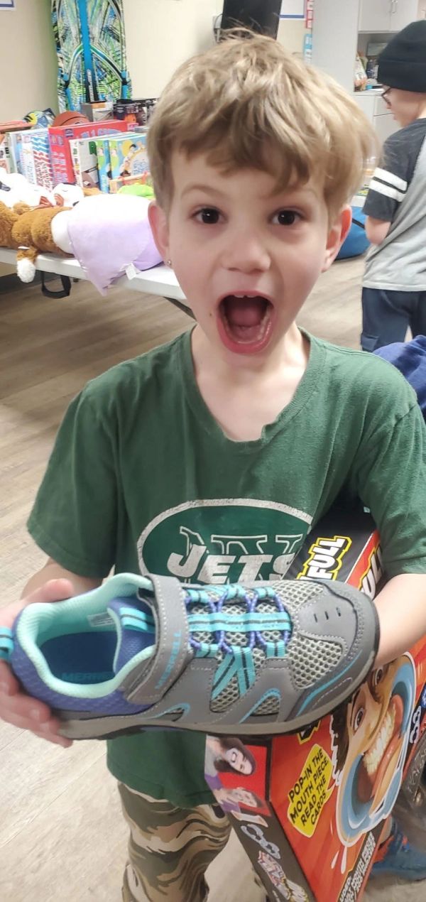 Excited boy holding a new shoe and game box.