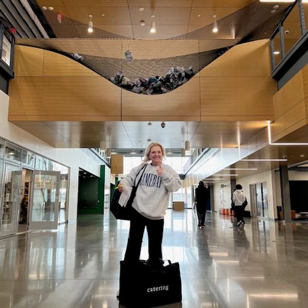 Person standing in modern building hallway with a tote bag.