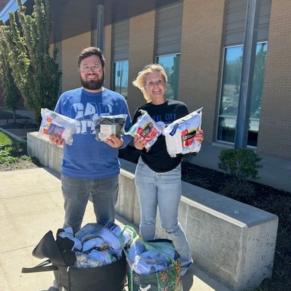 Two people holding packaged goods outside a building.