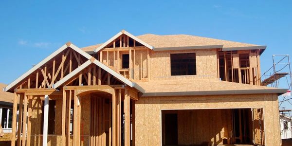 Wood-framed house under construction on a clear day.