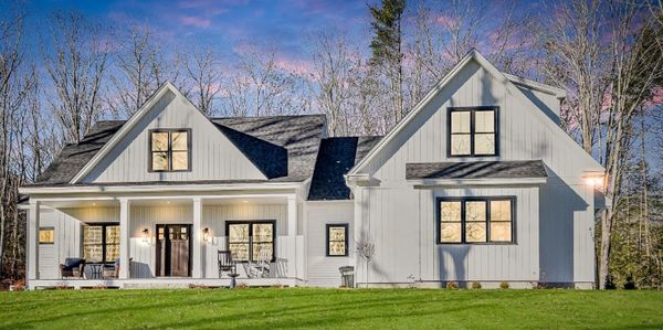 Modern farmhouse with white siding and black-trimmed windows at sunset.