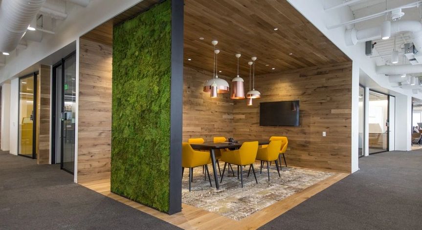 Modern office meeting space with yellow chairs and wood paneling.