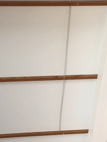 White ceiling with wooden beams and a hanging wire.
