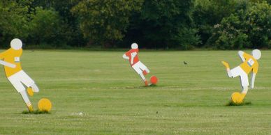 Cut-outs of three soccer players kicking a ball