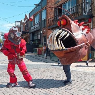 Two people in giant sea-themed costumes on a street.