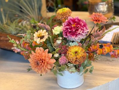 Colorful dahlia and zinnia flower bouquet in a white vase.