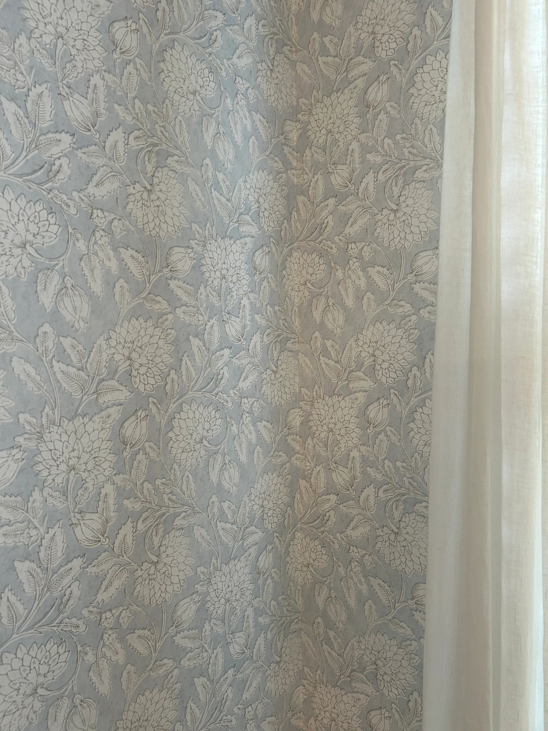 Elegant floral wallpaper in soft gray tones beside white curtains.
