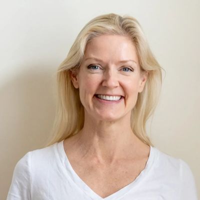 Smiling blonde woman in white shirt.