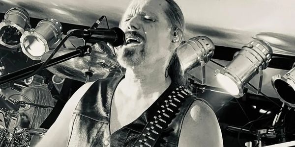 Black and white image of a male rock singer passionately performing on stage.