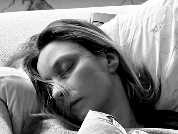 A woman peacefully sleeping on a couch with soft lighting.