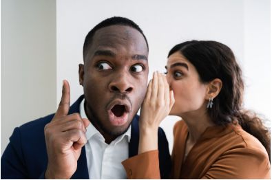 Woman whispering a secret to a man in a blue suit