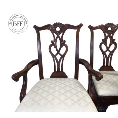 Pair of vintage wooden armchairs with intricate backrest carvings and patterned upholstery.