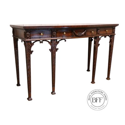 Elegant antique wooden table with intricate carvings and drawers.
