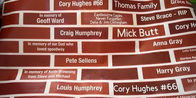 Wall with red brick-style plaques honoring various individuals.