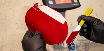 técnico experto realizando igualación de color personalizada con pintura roja metalizada y báscula 