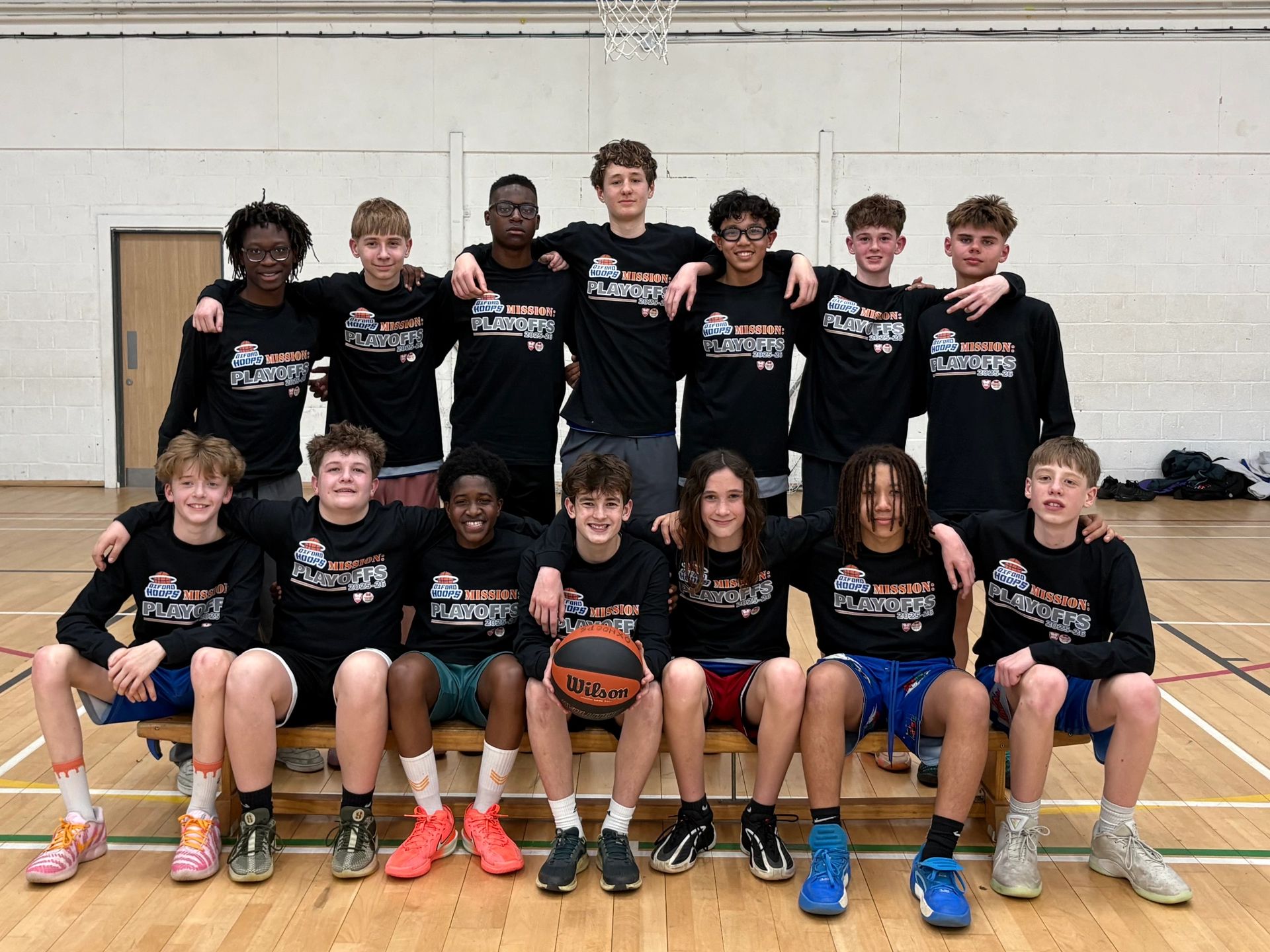 Youth basketball team posing together in matching playoff shirts in a gym.