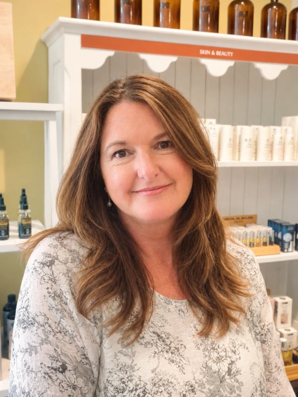 Smiling woman with long brown hair in a skincare store.