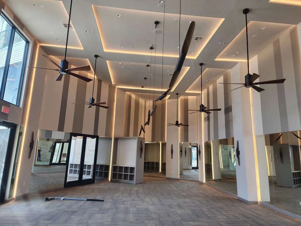 Modern room with ceiling fans, mirrors, and ambient lighting.