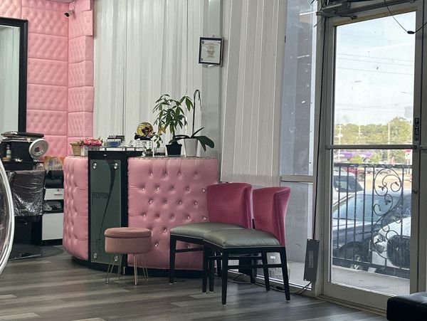 Pink-themed reception area with chairs and plants inside a beauty salon.