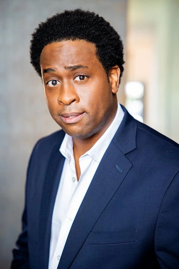 Man in a navy suit with a curious expression.