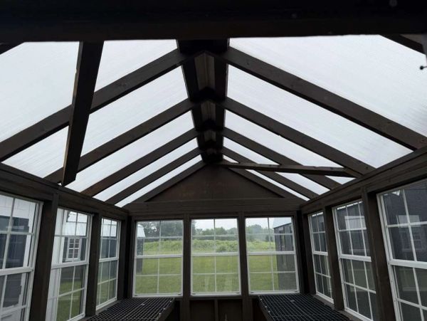 Interior view of a greenhouse with translucent roof and windows.