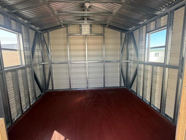 Empty metal shed with wooden floor and windows on both sides.