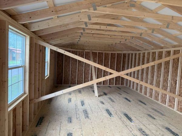 Empty wooden shed interior under construction with windows.