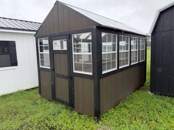 Small brown shed with windows and double door.