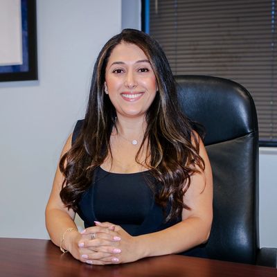 Woman sitting at an office desk, smiling.