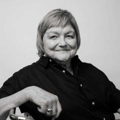 Older woman smiling in black and white portrait.