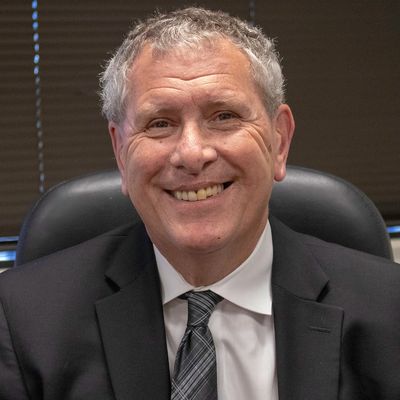 Smiling man in a suit seated in an office chair.