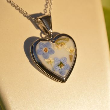 Heart-shaped pendant with pressed flowers on a chain.