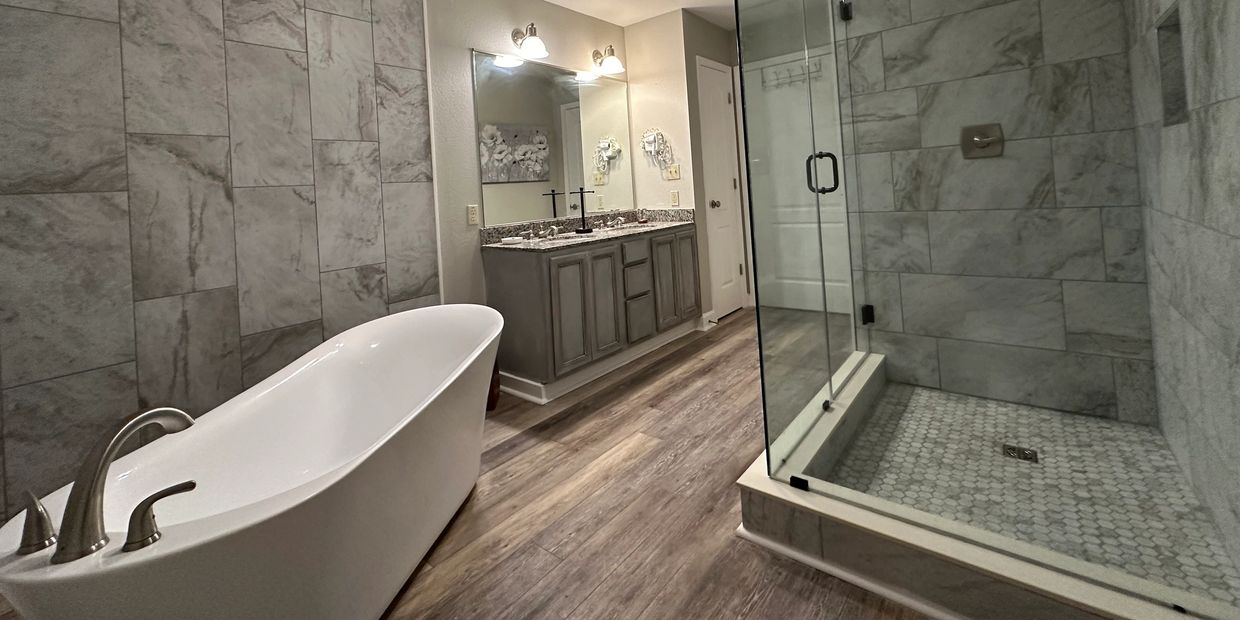 Modern bathroom with freestanding tub, glass shower, and wooden floor.