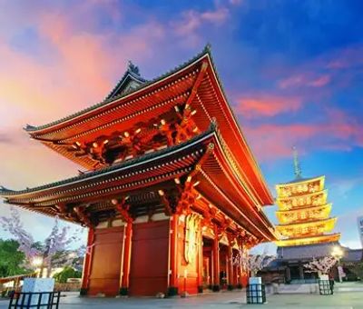 Traditional Japanese temple and pagoda at sunset with vibrant sky.