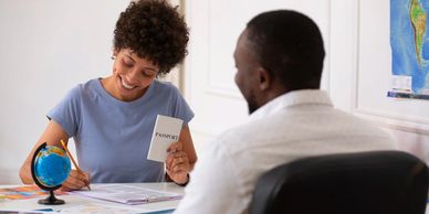 Woman happily holding a passport while filling out forms with a man.