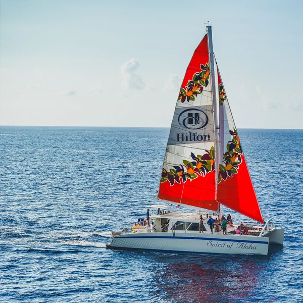 Catamaran named Spirit of Aloha with red sail on the ocean.