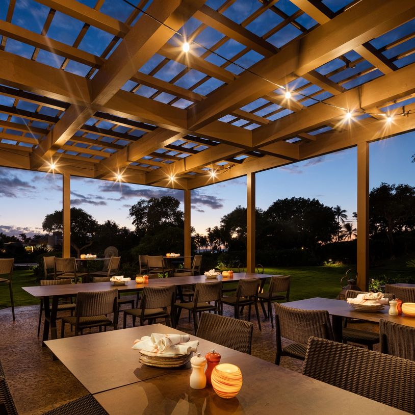 Outdoor restaurant seating under string lights at dusk.