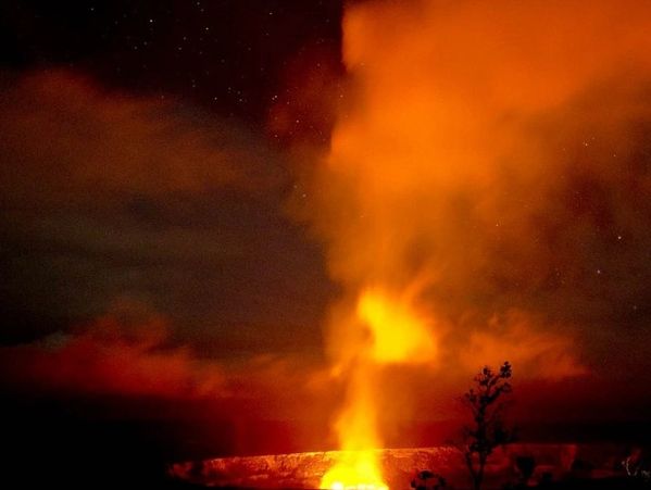 Volcanic eruption with fiery glow and smoke at night.