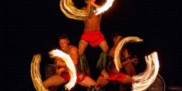 Performers twirling fire sticks in a traditional dance.