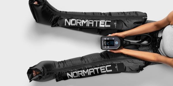 Person using Normatec compression boots for recovery.