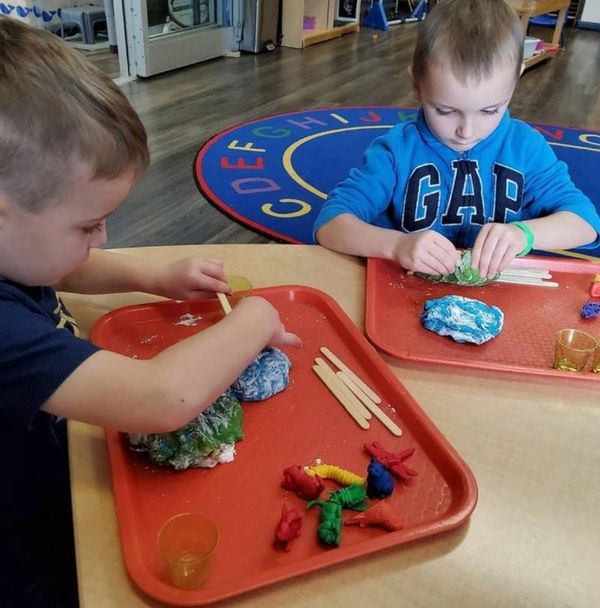 Two children sitting at a table playing with playdough.  