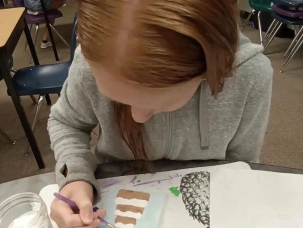 A child sitting at a table drawing a picture.