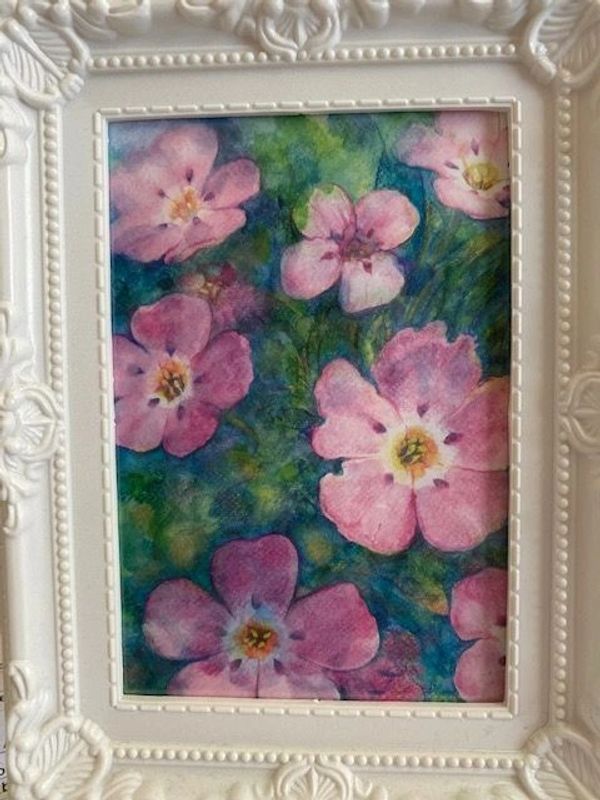 Watercolor painting of pink flowers with green and blue background in ornate white frame.