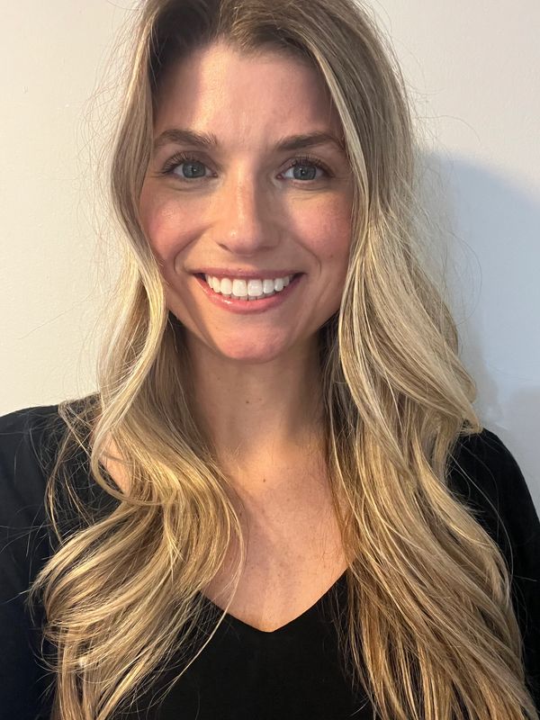 Smiling woman with long blonde hair wearing a black top.