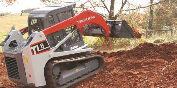 Takeuchi TL8 compact track loader working on a dirt slope.